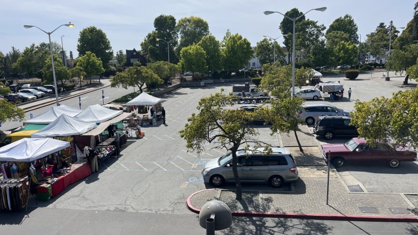 An outdoor parking lot on a sunny day filled with several tents and people selling their wares